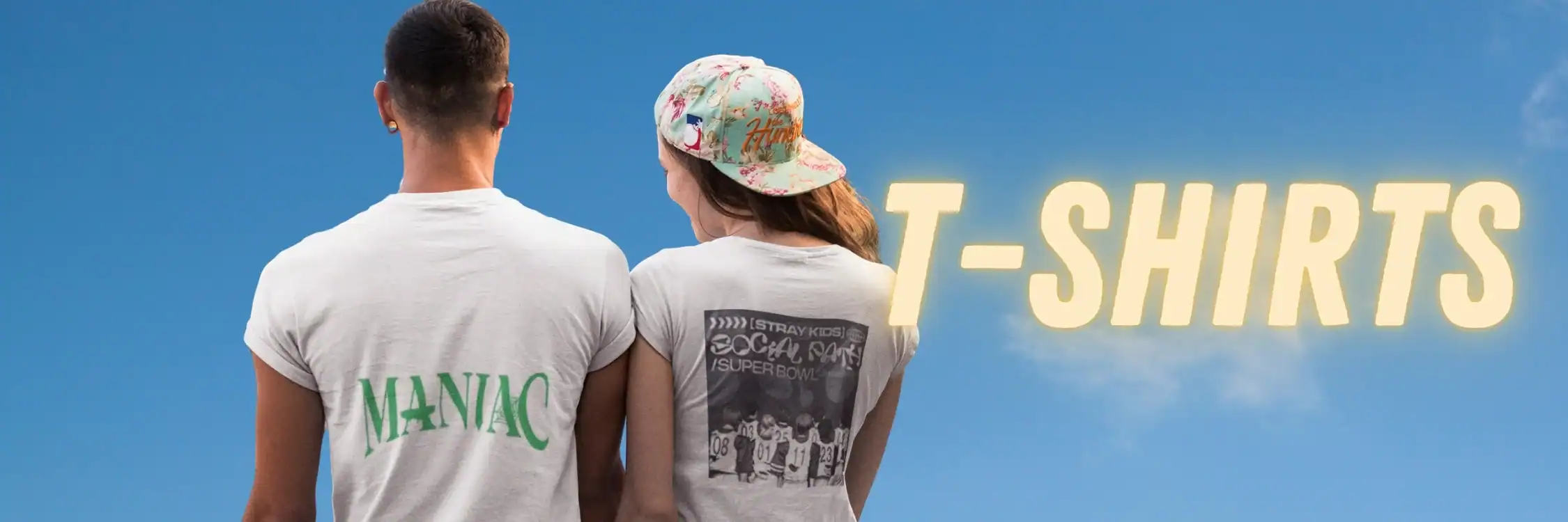 Maniac graphic T-shirt with green lettering on white fabric, worn by a person standing outdoors.