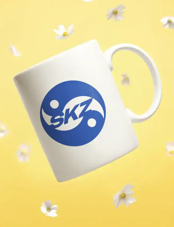 Skz logo on white ceramic mug with floating flowers and yellow background.