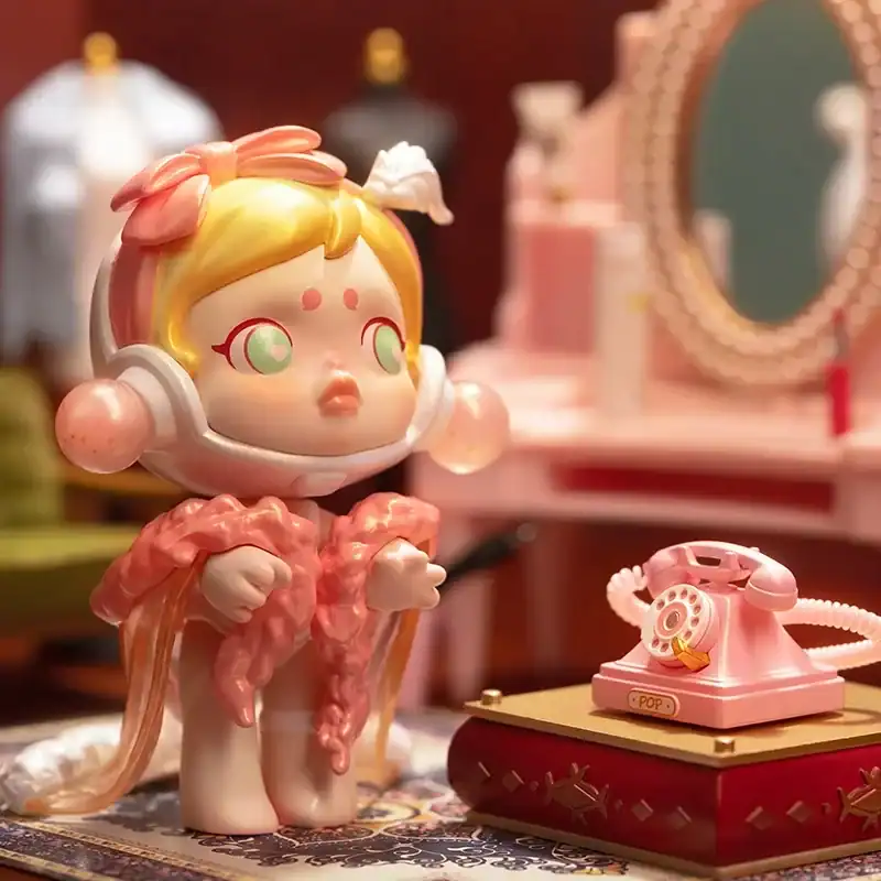 Cute anime-style figure with headphones, colorful hair, and pastel outfit, placed on a vintage pink vanity with a rotary phone in a cozy room setting.