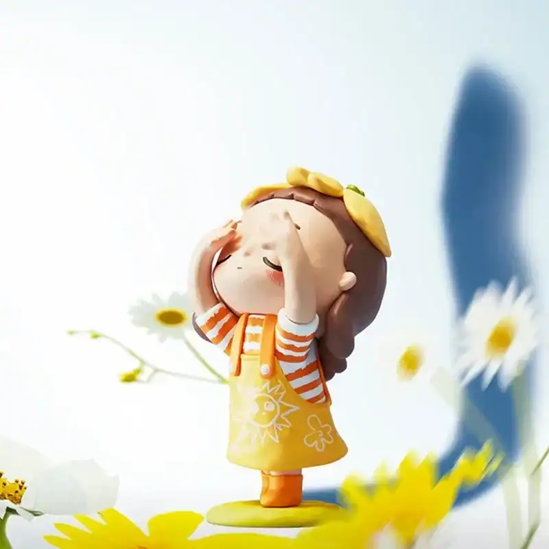 Colorful K-pop merchandise figurine of a girl in a yellow dress with daisies and orange striped shirt, holding her head with a playful expression.