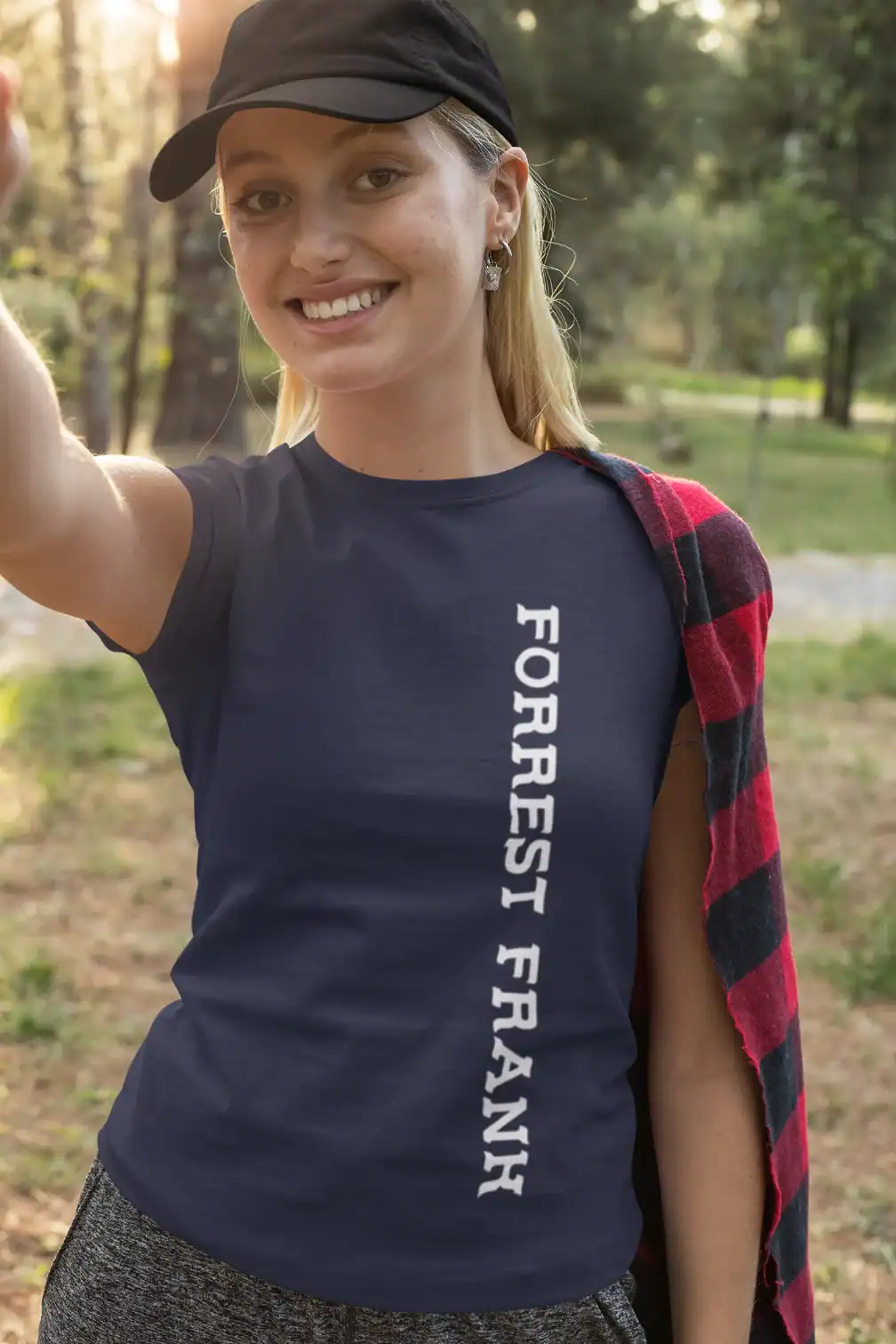 Forest girl wearing a navy t-shirt with white text, outdoors in a park during sunset, casual style, smiling woman, nature background.
